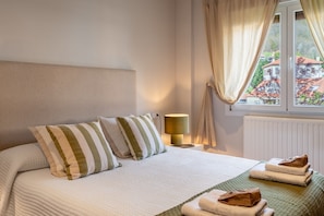 A neatly made bed with striped pillows, a bedside lamp, and a window with curtains.