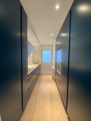 A narrow, modern kitchen with a window, a built-in oven, and a countertop with a sink. - Socaire Apartment in Ribadesella – Central, Renovated, Near the Beach (Ribadesella)