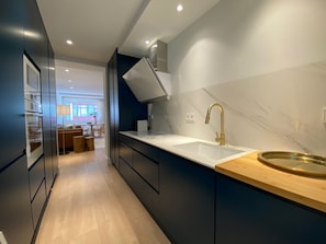 Eine moderne Küche mit Marmorfliesenspiegel, einer Holz Arbeitsplatte und einer eingebauten Spüle.
