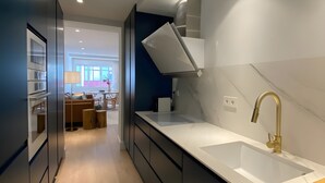A modern kitchen with a white countertop, a gold faucet, and a dark backsplash. - Socaire Apartment in Ribadesella – Central, Renovated, Near the Beach (Ribadesella)
