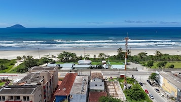 A coastal cityscape with a beach, buildings, and a prominent hill in the distance.