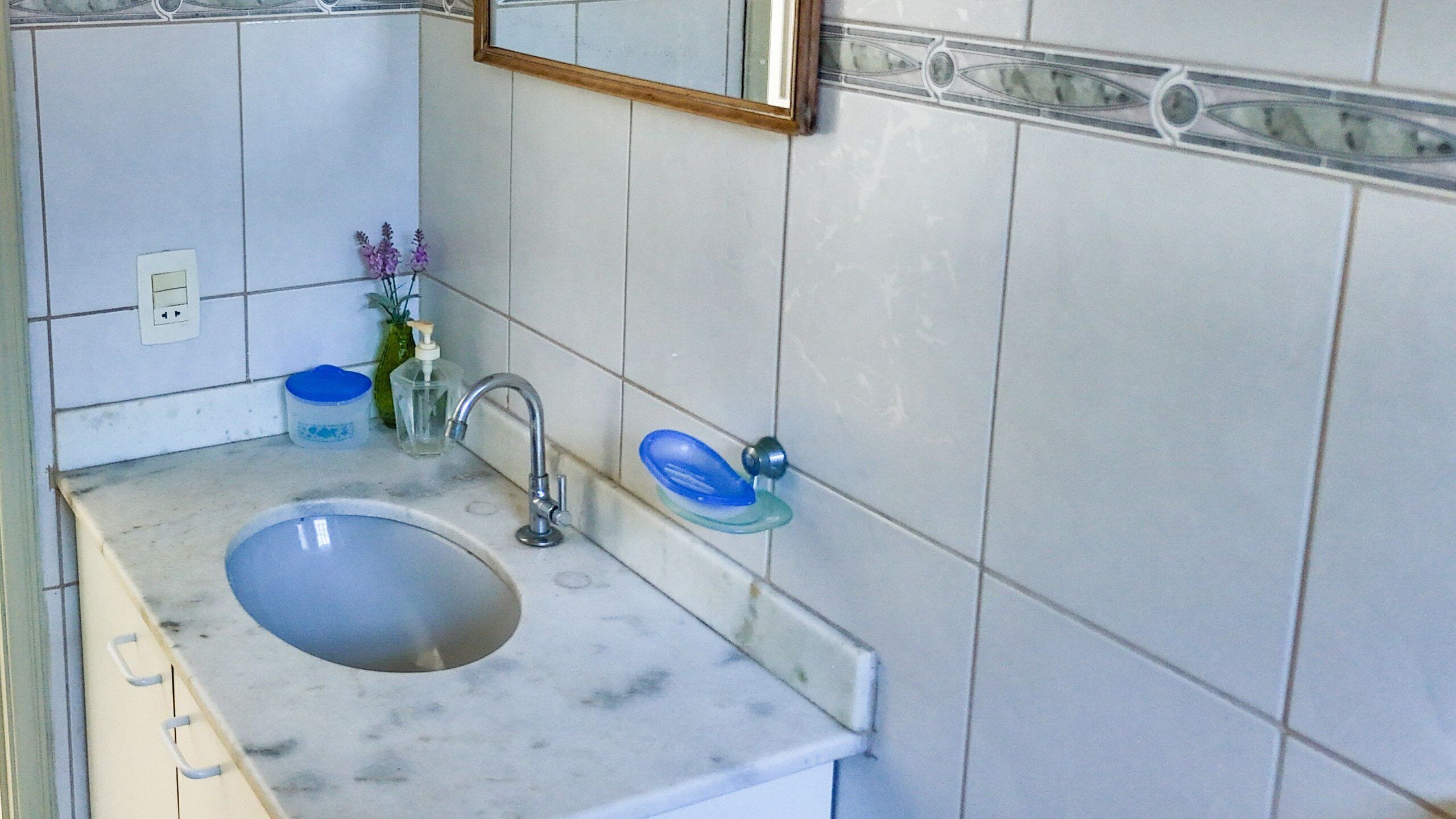 A bathroom with a sink, mirror, and tiled walls.