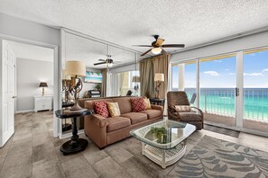 Ein geräumiges Wohnzimmer mit großem Fenster, Deckenventilator und Meerblick.