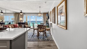 A spacious room with a large window, a dining area with a table and chairs, and a ceiling fan. - 8th-Floor Beachfront Condo with Curved Balcony (Panama City Beach)