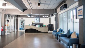 A hotel reception area with a modern design, including a reception desk, seating area, and a view of the city through large windows.