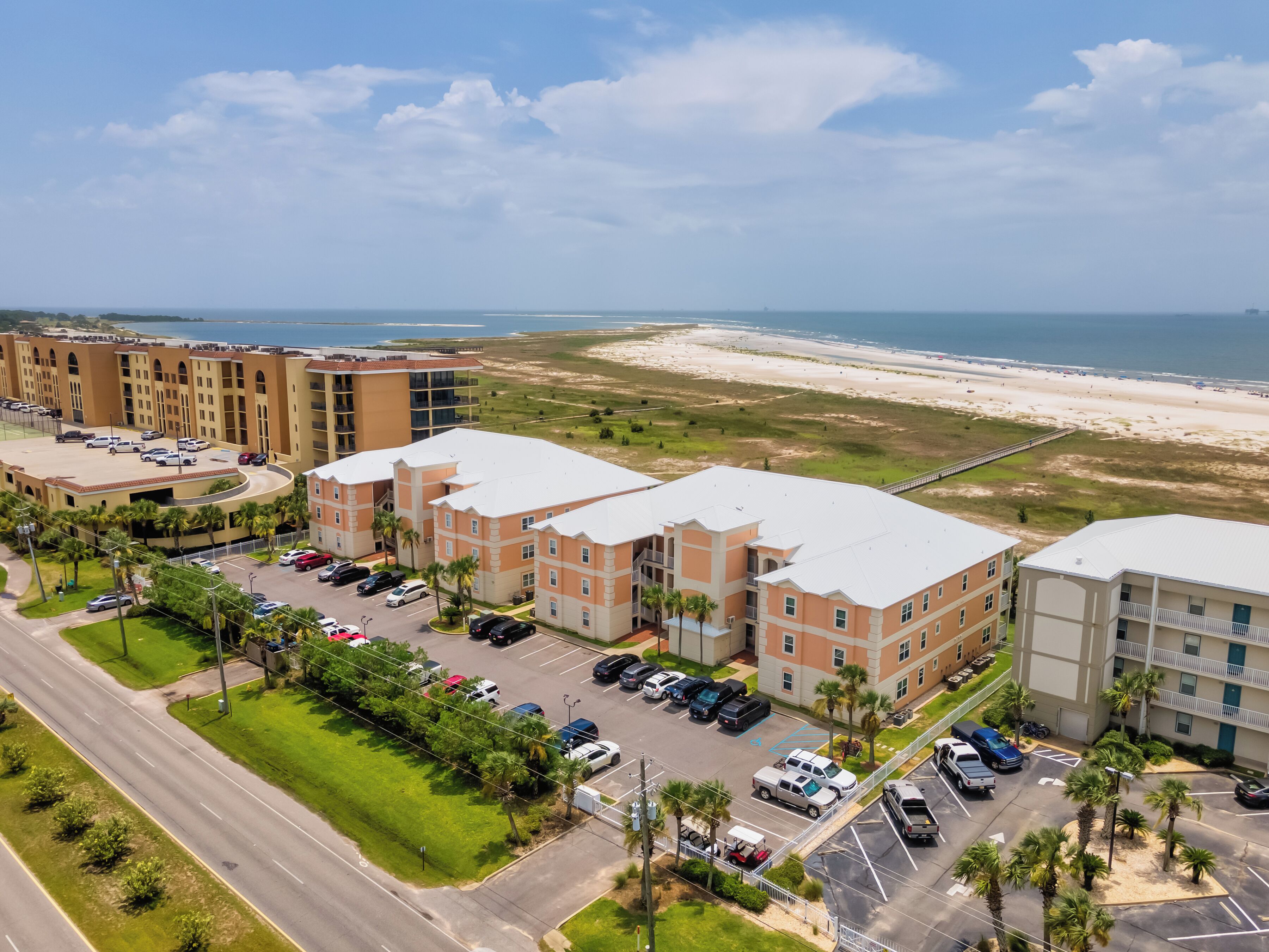 A hotel with multiple buildings, parking lots, and a beach view.