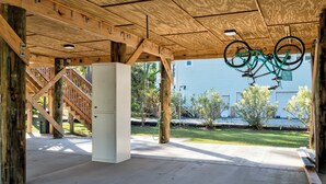 Estructura de madera abierta con piso de concreto, un gabinete blanco y una bicicleta colgando del techo.