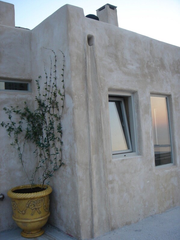 A building with a stucco exterior, a window, and a potted plant. - Villa Piperi - Allparos Villas for 4-6 (Paros)