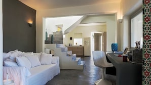 Ein modernes Wohnzimmer mit einer Couch, einem Essbereich mit einem Stuhl und einer Treppe, die in eine Küche führt.