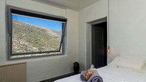 Ein Schlafzimmer mit einem großen Fenster und Blick auf eine gebirgige Landschaft.