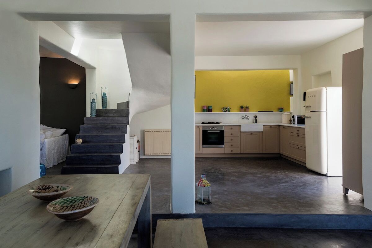 A modern kitchen with a yellow accent wall, a built-in oven, and a refrigerator.