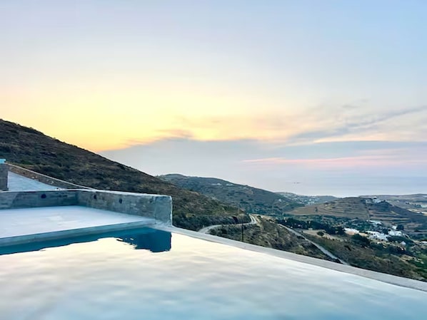 A concrete structure with a flat roof overlooking a hilly landscape and a distant view of a town.
