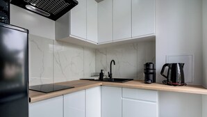 Une cuisine moderne avec des meubles blancs, un robinet noir, une machine à café et un appareil électroménager noir.