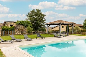 Ein Schwimmbad mit Liegestühlen, einer Pergola und Steinmauern.