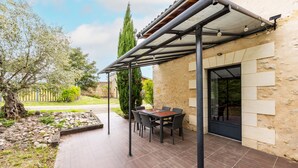 An outdoor patio with a table and chairs, a pergola, and a stone wall. - Gîte L'Ombrière with Shared Pool, Communal Terrace and Wi-Fi (Saint-Caprais de Bordeaux)