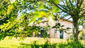A building with a stone facade, large windows, and a covered outdoor seating area. - Gîte L'Ombrière with Shared Pool, Communal Terrace and Wi-Fi (Saint-Caprais de Bordeaux)
