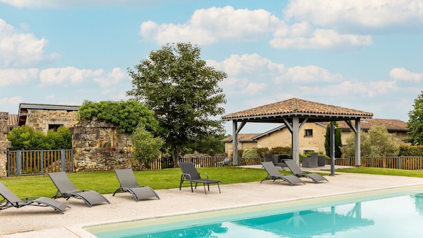 A swimming pool with lounge chairs, a pergola, and stone walls. - Gîte L'Ombrière with Shared Pool, Communal Terrace and Wi-Fi (Saint-Caprais de Bordeaux)