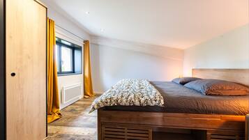 A bedroom with a wooden bed, a window with curtains, and a radiator.