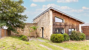 A stone building with a wooden extension, a paved path, and a tree. - Holiday Home 'Gîte Loft' with Shared Pool, Communal Terrace and Wi-Fi (Saint-Caprais de Bordeaux)