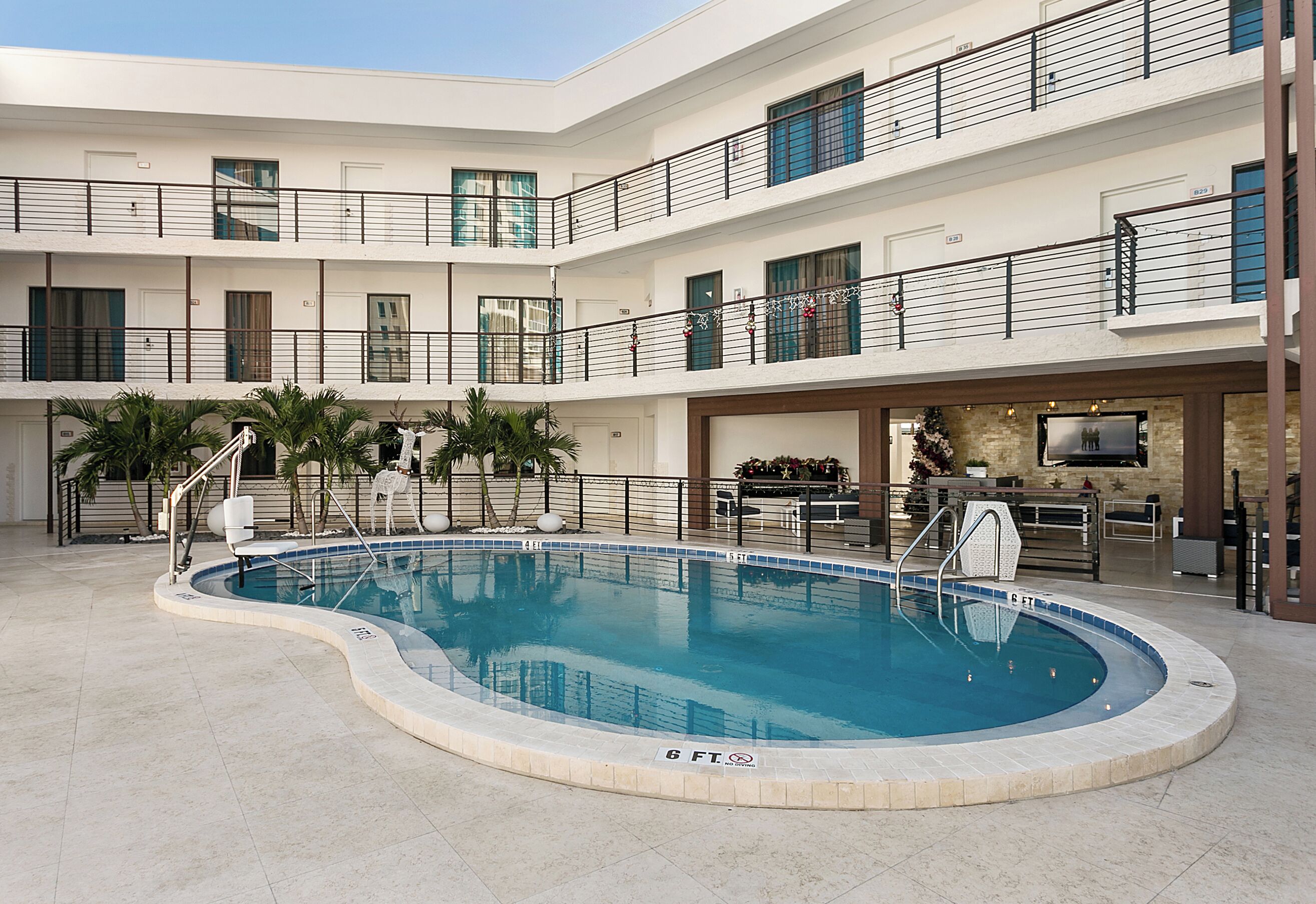 A multi-level hotel with a central swimming pool, balconies, and a reception area.