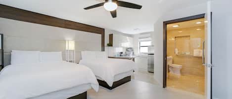 A modern bedroom with two beds, a ceiling fan, and a bathroom visible through an open door.