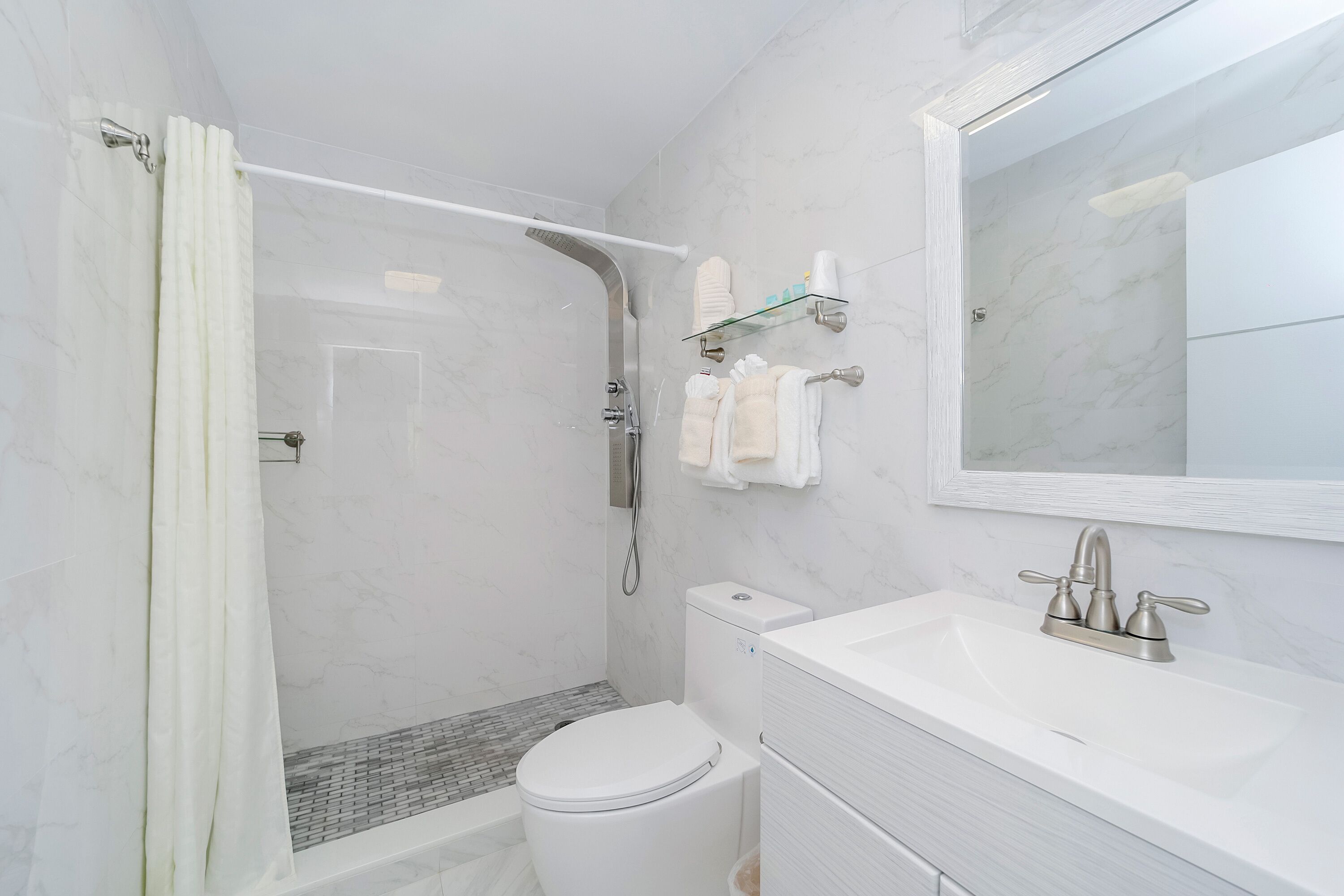 Een moderne badkamer met douche, toilet en wastafel.