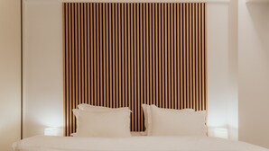 Een net opgemaakt bed met witte lakens in een kamer met een houten lattenbovenstuk.