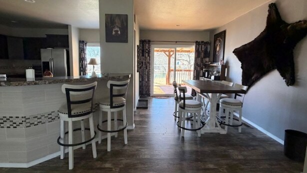 Uma cozinha com uma ilha central, banquetas de bar e uma mesa de jantar com cadeiras.