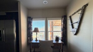 Uma cozinha compacta com geladeira, uma mesa de jantar com cadeiras e uma janela com cortinas.