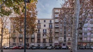A multi-story residential building with balconies, parked cars, and a street in the foreground. - Cozy Flat near Inalpi Arena by Wonderful Italy (Turin)