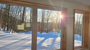 A room with large windows offering a view of a snowy landscape and trees.