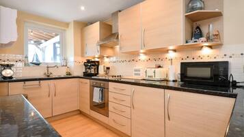 A modern kitchen with wooden cabinets, a built-in oven, a microwave, and a coffee maker.