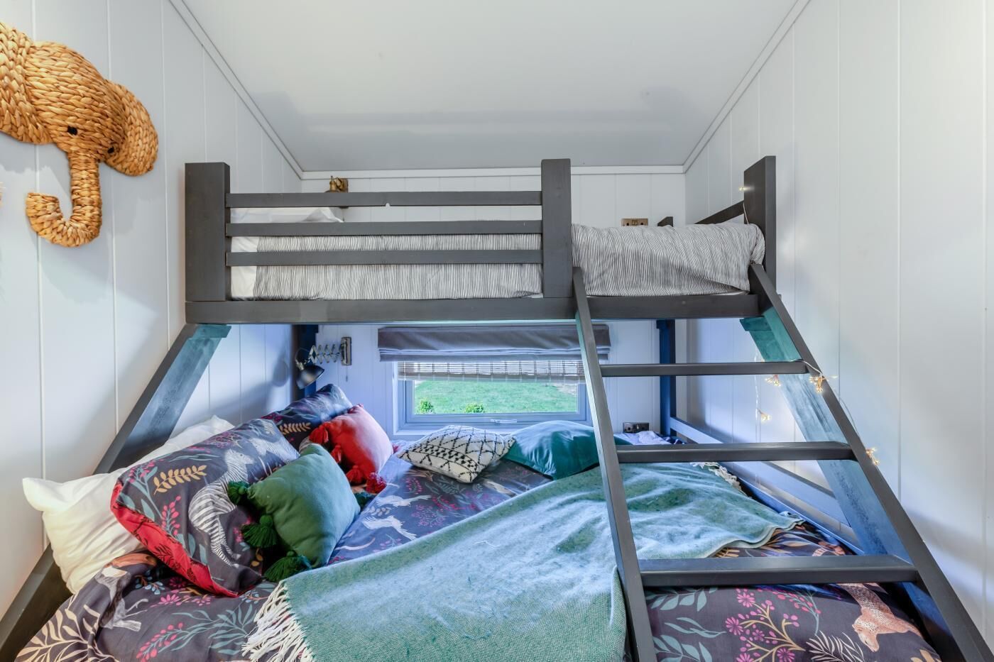 Un letto a castello con finestra, cuscini e una decorazione di elefante intrecciato.