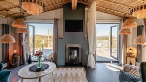 A room with a high ceiling, a fireplace, a round table with a vase of flowers, and large windows with curtains. - 2 Bed in Pensilva (oc-s30446) (Pensilva)