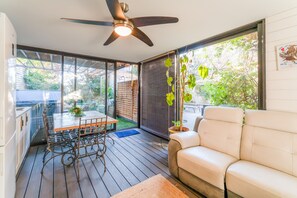 Un patio moderne avec une table à manger, des chaises, un ventilateur de plafond et un canapé.