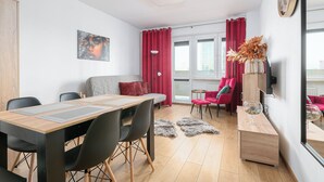 Moderni olohuone, jossa on puinen ruokapöytä, mustat tuolit, punainen sohva ja punainen nojatuoli.