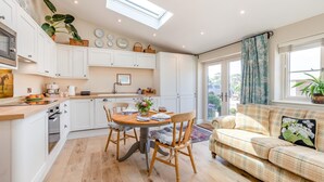 A modern kitchen with white cabinets, a dining table with chairs, and a sofa in the living area. - 1 Bed in Ashton (oc-p30484) (Ashton)
