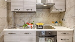 Una cucina moderna con lavello in acciaio inossidabile, forno integrato e un piano di lavoro con una ciotola di verdure e pasta.
