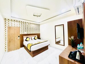 A hotel room with a bed, a desk, a mirror, a plant, and a wall-mounted air conditioner. - Hotel Sm Eagle Grand Airport Zone Hyd (Hyderabad)