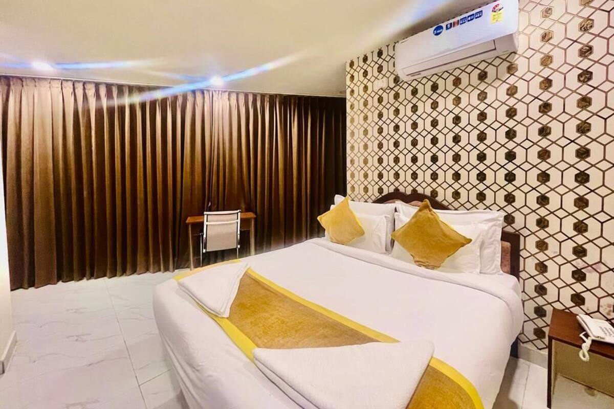 Une chambre d’hôtel avec un grand lit, un mur décoré d’un motif, un appareil de climatisation et un téléphone sur une table de chevet.