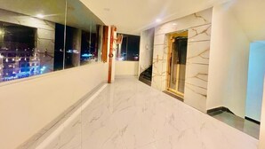 A modern hallway with a marble floor, large windows, and a staircase leading to an upper level. - Hotel Sm Eagle Grand Airport Zone Hyd (Hyderabad)