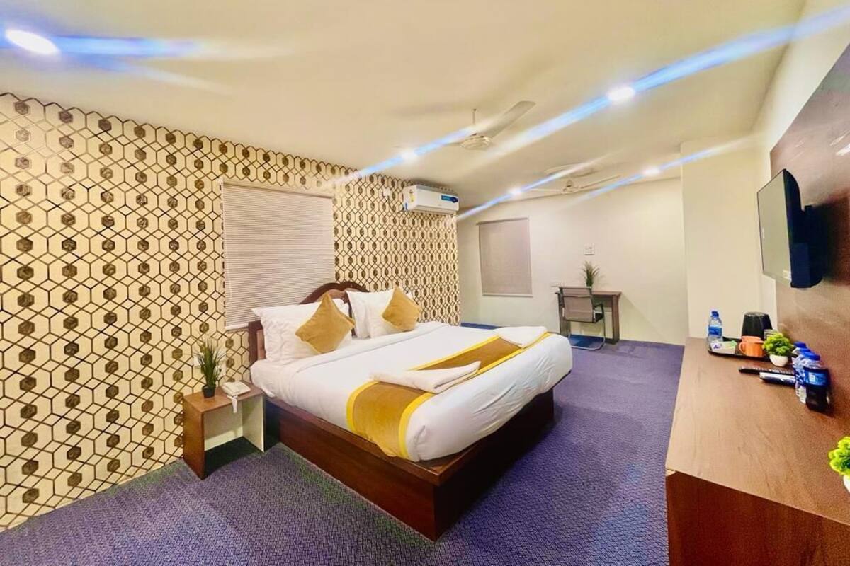 Une chambre d’hôtel avec un lit, un bureau, un miroir et un mur décoré de motifs.