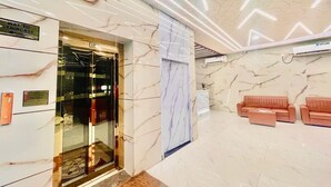 A lobby with a marble floor, a reception desk, a sign indicating the way to the staircase, and a seating area with sofas. - Hotel Sm Eagle Grand Airport Zone Hyd (Hyderabad)