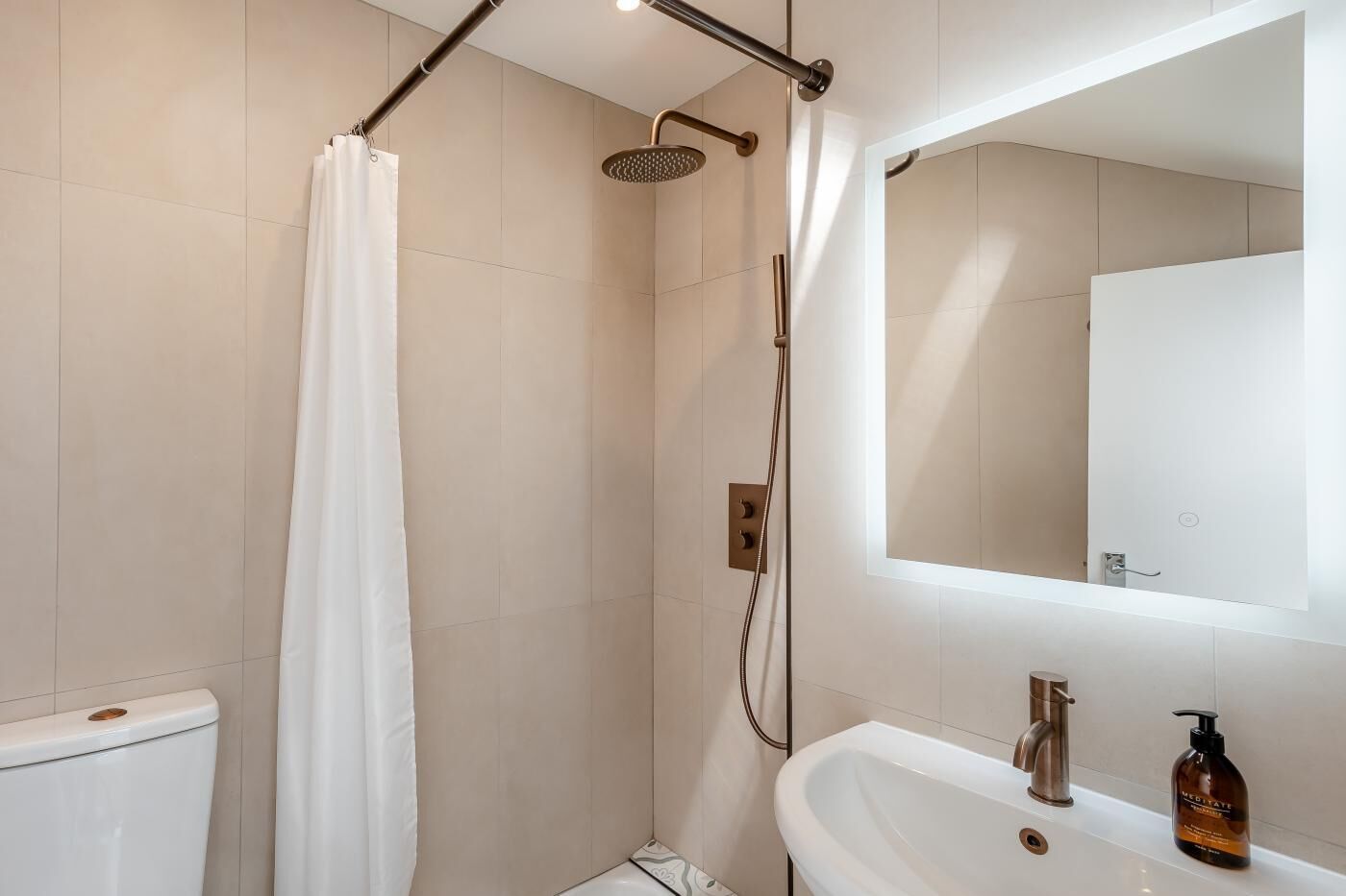 Ein modernes Badezimmer mit Dusche, Toilette, Waschbecken und Spiegel.
