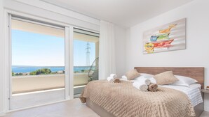 A bedroom with a bed, a view through a sliding door, and a painting on the wall. - Charming Seaside Villa Getaway (Splitsko-dalmatinska župani)