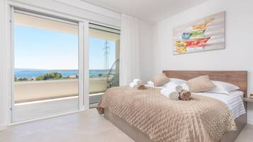 Een slaapkamer met een bed, uitzicht door een schuifdeur en een schilderij aan de muur.