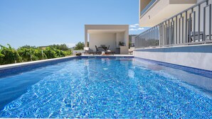 A swimming pool with a tiled edge, a covered seating area, and a balcony with railings. - Charming Seaside Villa Getaway (Splitsko-dalmatinska župani)