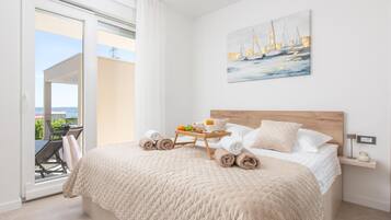 A bedroom with a bed, a painting, a bedside table, and a view of the outside.