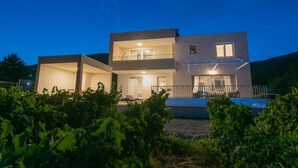 A modern two-story house with a balcony, a swimming pool, and a vineyard in the foreground. - Charming Seaside Villa Getaway (Splitsko-dalmatinska župani)