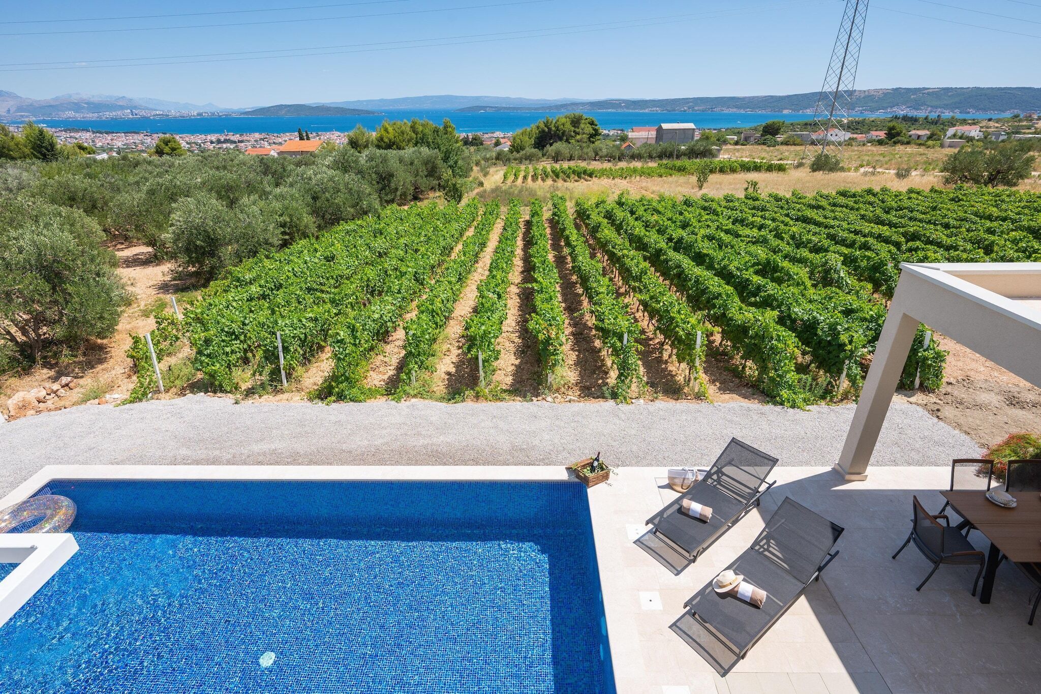 A pool with lounge chairs and a view of a vineyard.
